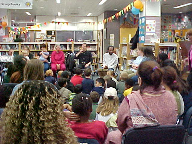 Kwabena answers questions with signing from kids & adults in a library